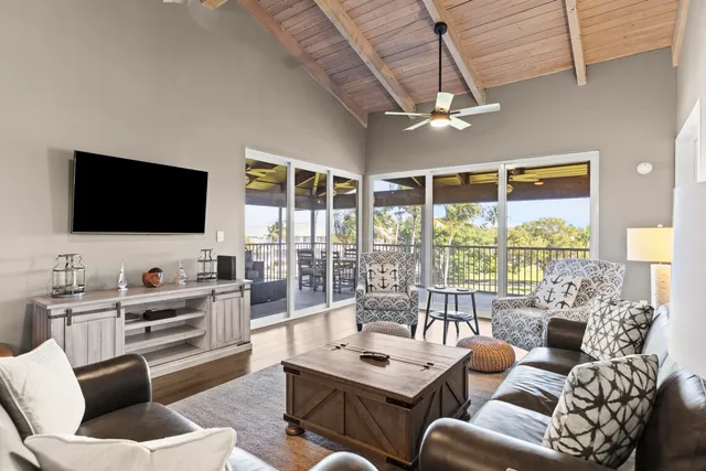 a living room with furniture a flat screen tv and a floor to ceiling window