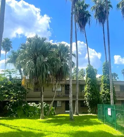 a view of a house with a big yard and palm trees