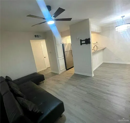 a living room with wooden floor and a ceiling fan
