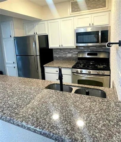 a kitchen with granite countertop a stove and a refrigerator