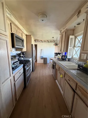 a kitchen with stainless steel appliances a stove a sink dishwasher a refrigerator and a stove