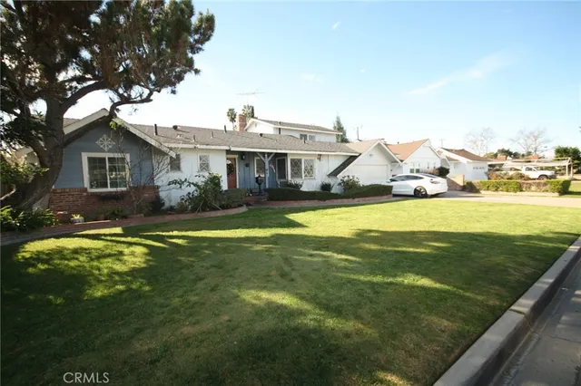 a view of a house with a big yard potted plants and large tree