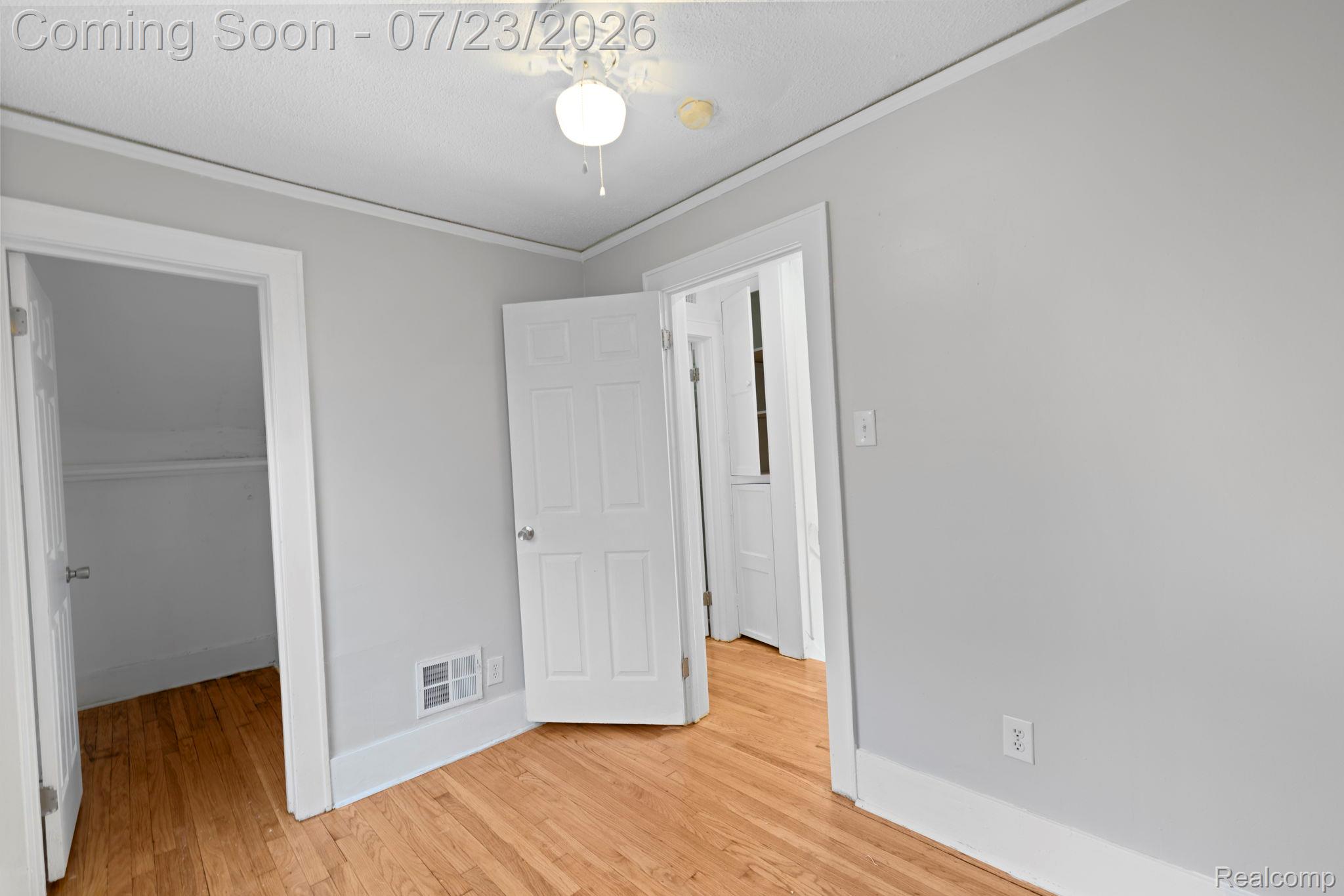 74 Pine Street River Rouge, MI 48218 - Photo 19 of 29 Unfurnished bedroom featuring a walk in closet, ornamental molding, light wood-type flooring, and ceiling fan