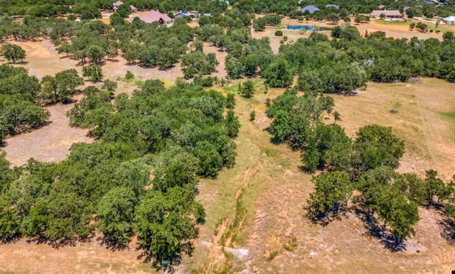 an aerial view of residential house with outdoor space and trees all around