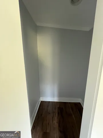 an empty room with wooden floor cabinet and windows
