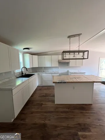a kitchen with kitchen island granite countertop a sink and white cabinets