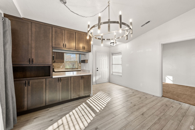 301 South 1200th Street East, Unit 31 St. George, UT 84790 - Photo 16 of 21 Kitchen with dark wood finish cabinetry, light countertops, lofted ceiling, hanging lights, and light wood-style flooring