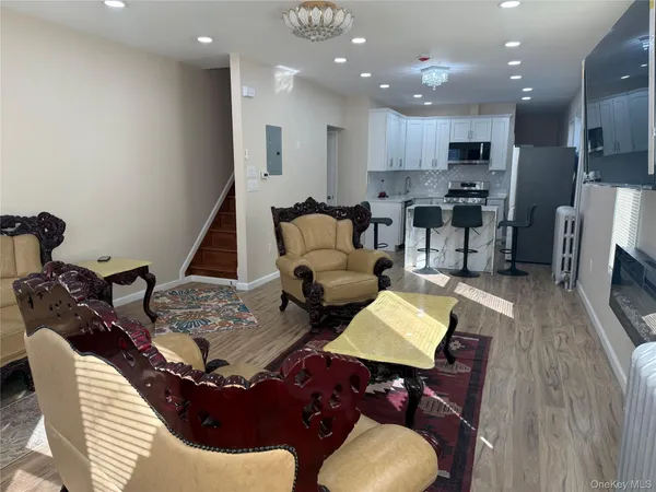 a living room with furniture kitchen view and a chandelier