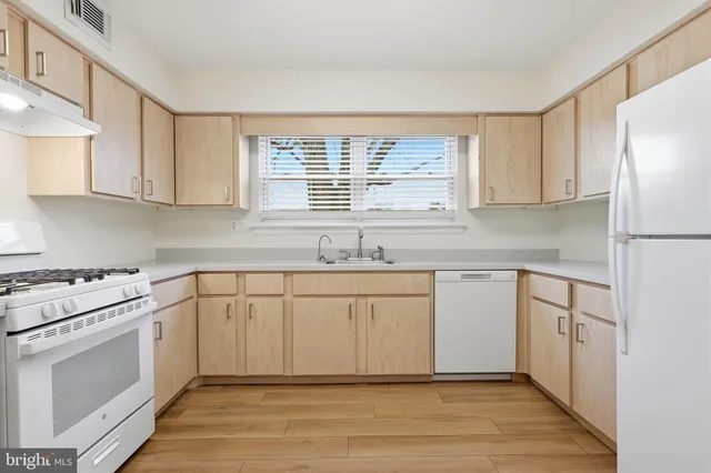 a kitchen with granite countertop a sink cabinets stainless steel appliances and a window