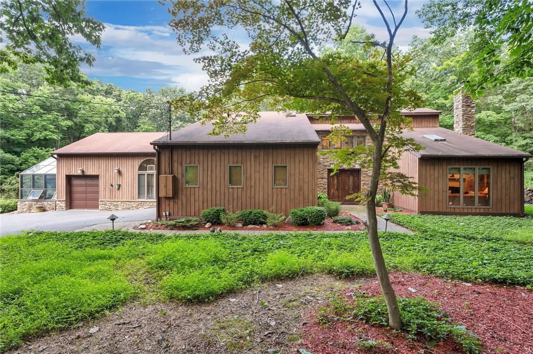 a front view of a house with garden and trees