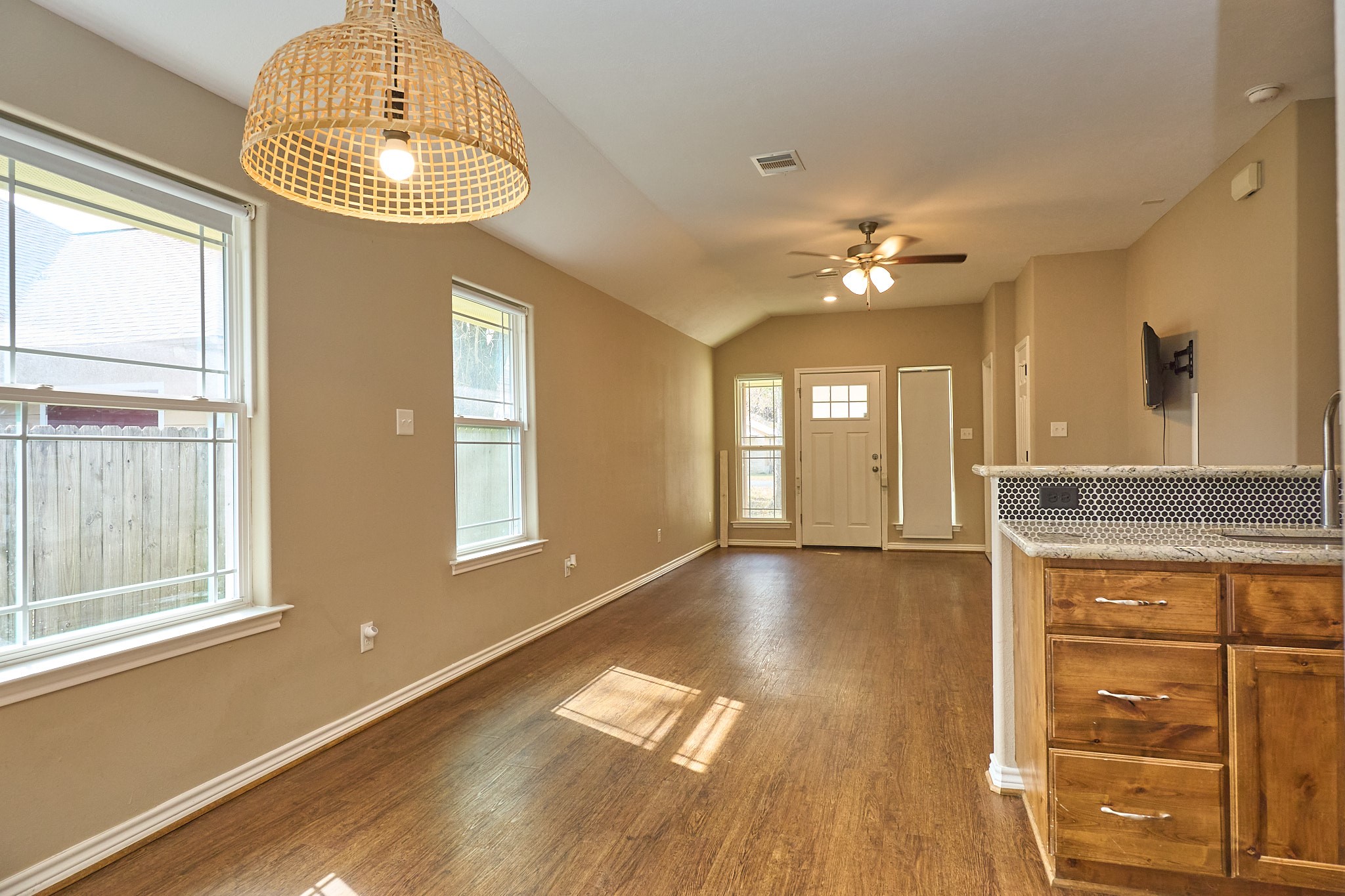 1807 Nuches Lane Bryan, TX 77803 - Photo 12 of 27 This cozy, well-lit living space features hardwood floors, a stylish light fixture, and an open layout with a small bar area. Large windows bring in natural light, and a ceiling fan provides comfort. Ideal for intimate gatherings and relaxed living.