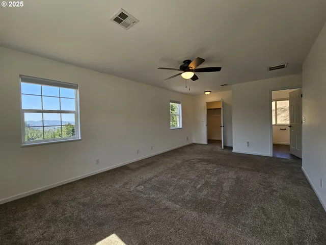 an empty room with windows and ceiling fan