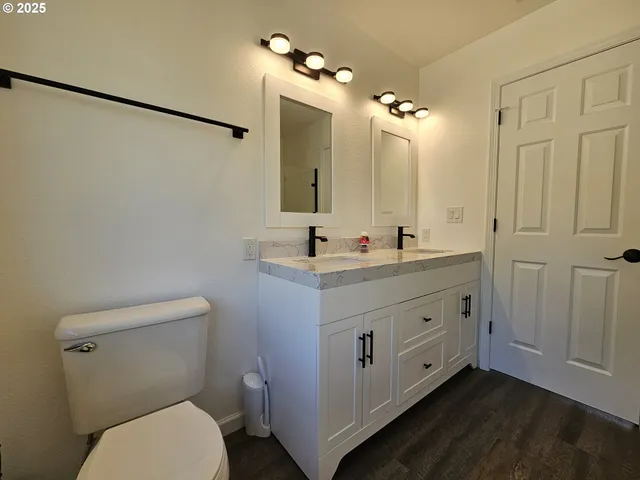 a bathroom with a double vanity sink a toilet a mirror and vanity