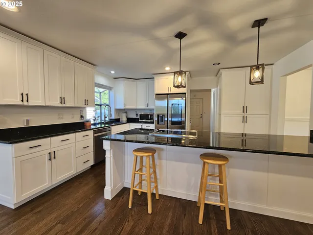 a kitchen with granite countertop white cabinets white appliances with a dining table and chairs