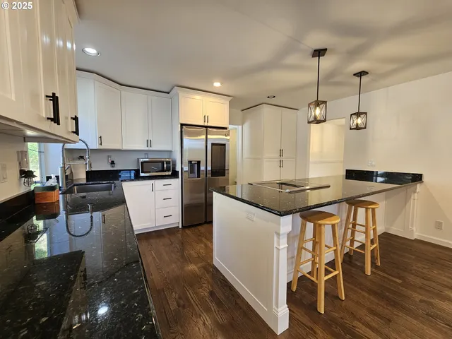 a kitchen with granite countertop white cabinets and stainless steel appliances