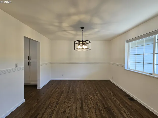 an empty room with wooden floor cabinet and windows