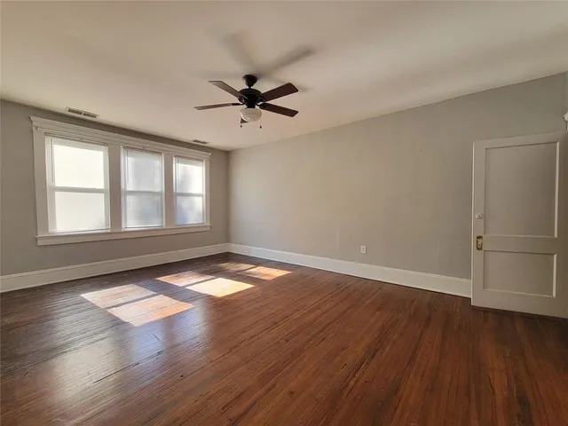 a view of empty room with wooden floor and fan