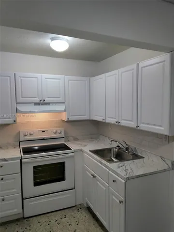 a kitchen with granite countertop white cabinets and white appliances