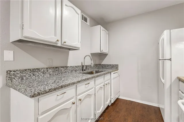 a kitchen with granite countertop a white cabinets and refrigerator
