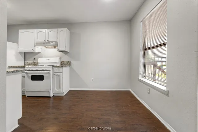 a kitchen with a stove a sink and white cabinets