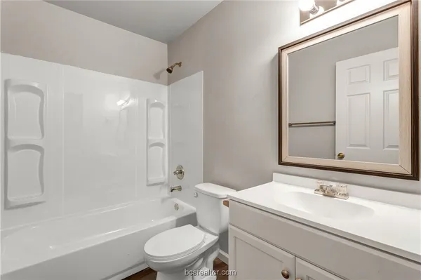a bathroom with a granite countertop sink toilet a mirror and shower