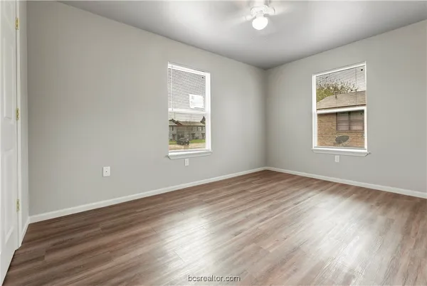 an empty room with wooden floor and windows