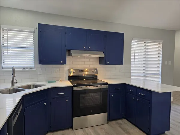 a kitchen with granite countertop stainless steel appliances a sink stove and cabinets