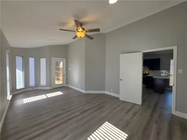 a view of empty room with wooden floor and window