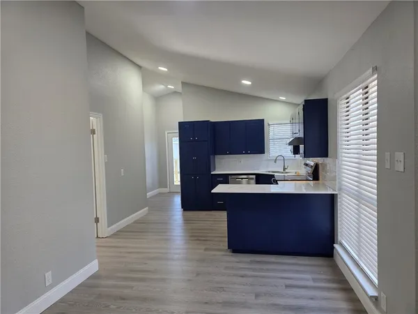 a large kitchen with stainless steel appliances granite countertop a sink and wooden floor