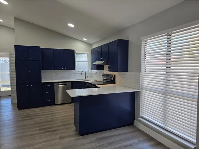 a kitchen with stainless steel appliances granite countertop a sink a stove and a refrigerator