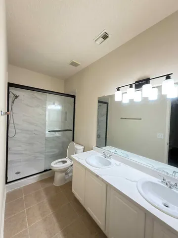 a bathroom with a double vanity sink toilet and shower