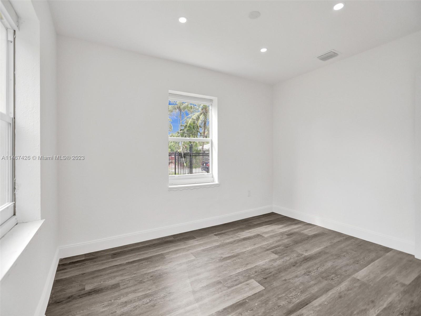 167 Northwest 84th Street Miami, FL 33150 - Photo 24 of 39 an empty room with wooden floor and windows