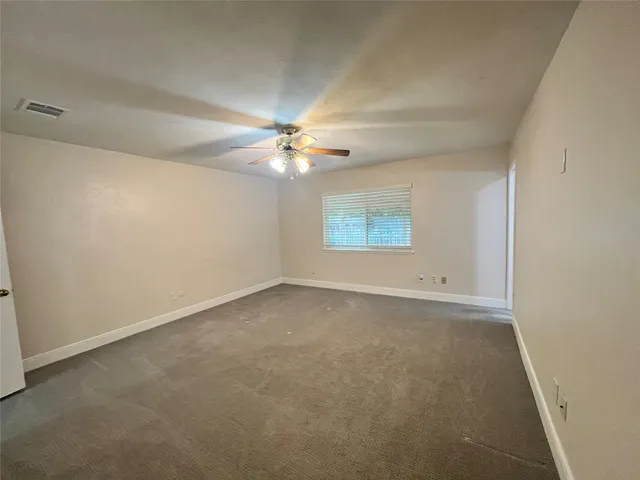 an empty room with a chandelier fan and windows