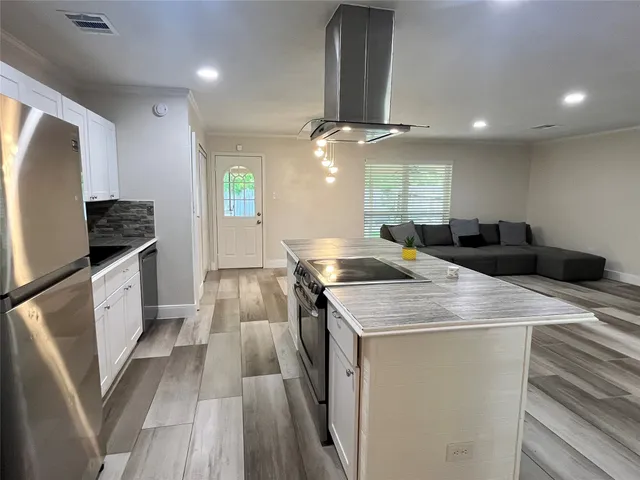 a kitchen with stainless steel appliances kitchen island granite countertop a sink a counter space and cabinets