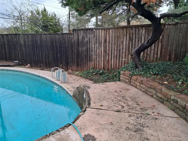 a view of a backyard with wooden fence and a large tree