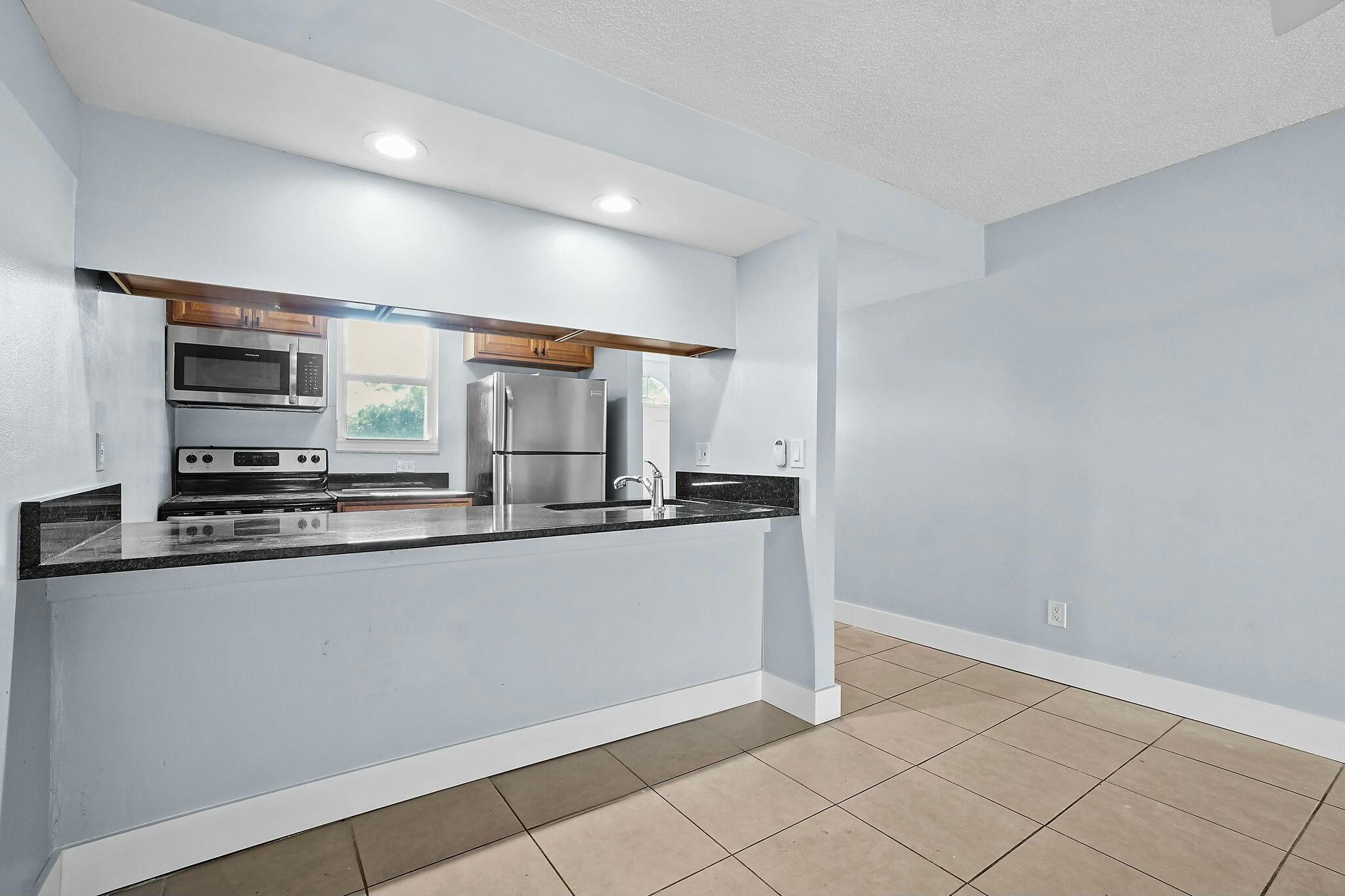 983 Northwest Spruce Ridge Drive, Unit 4 Stuart, FL 34994 - Photo 16 of 56 a kitchen with stainless steel appliances a sink and a refrigerator