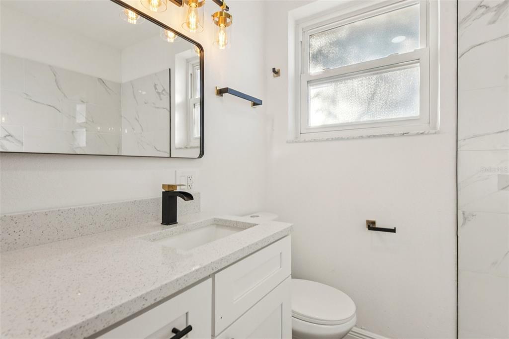 410 Virginia Avenue Madeira Beach, FL 33708 - Photo 15 of 25 a bathroom with a granite countertop sink mirror vanity and toilet