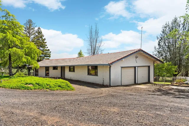 a view of a house with a yard and large trees