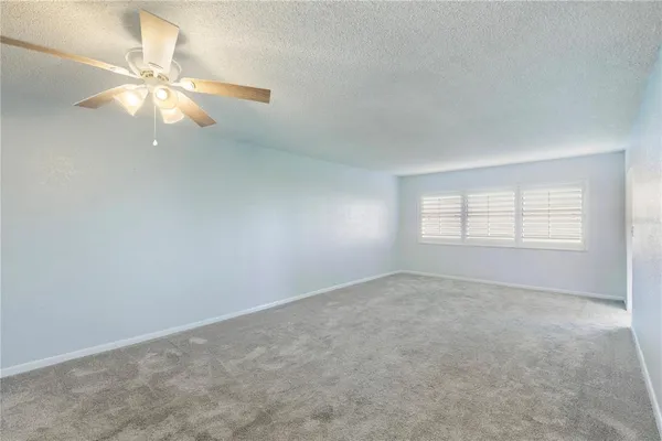 an empty room with windows and fan