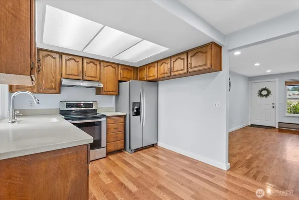 a kitchen with stainless steel appliances granite countertop a refrigerator a sink and a stove