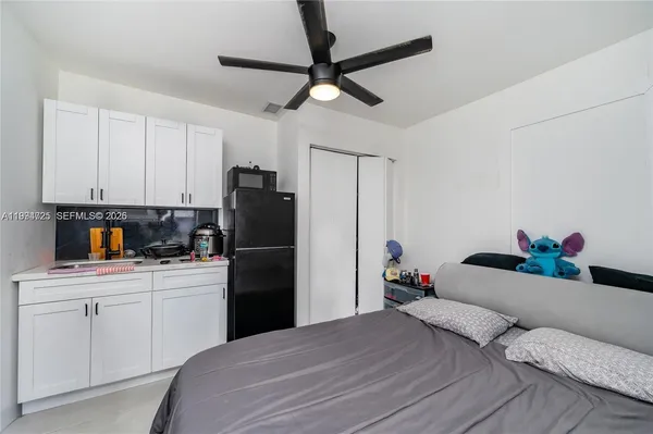 a bedroom with a bed and a refrigerator