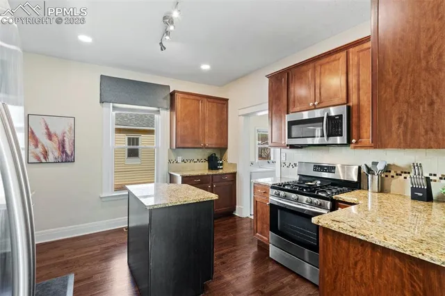 a kitchen with stainless steel appliances granite countertop a stove a sink and a microwave