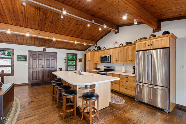 a kitchen with stainless steel appliances a table chairs refrigerator and wooden floors