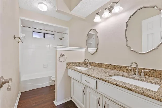 a bathroom with a granite countertop sink a mirror and a shower