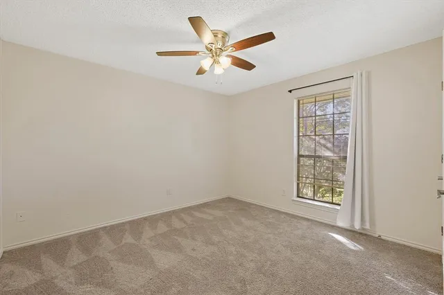 an empty room with ceiling fan and windows