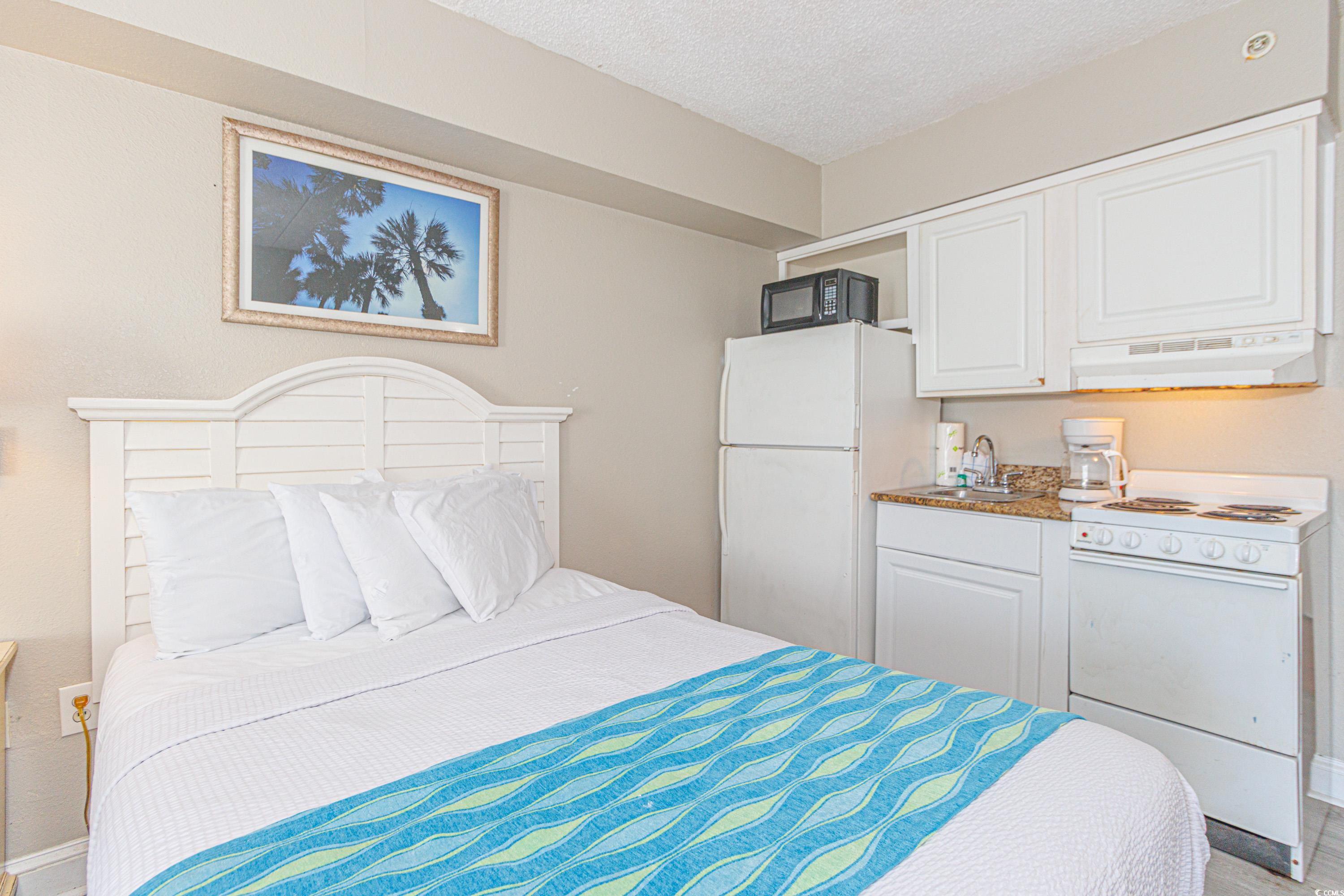 1207 South Ocean Boulevard, Unit 20703 Myrtle Beach, SC 29577 - Photo 11 of 22 Bedroom with sink, white refrigerator, and a textured ceiling