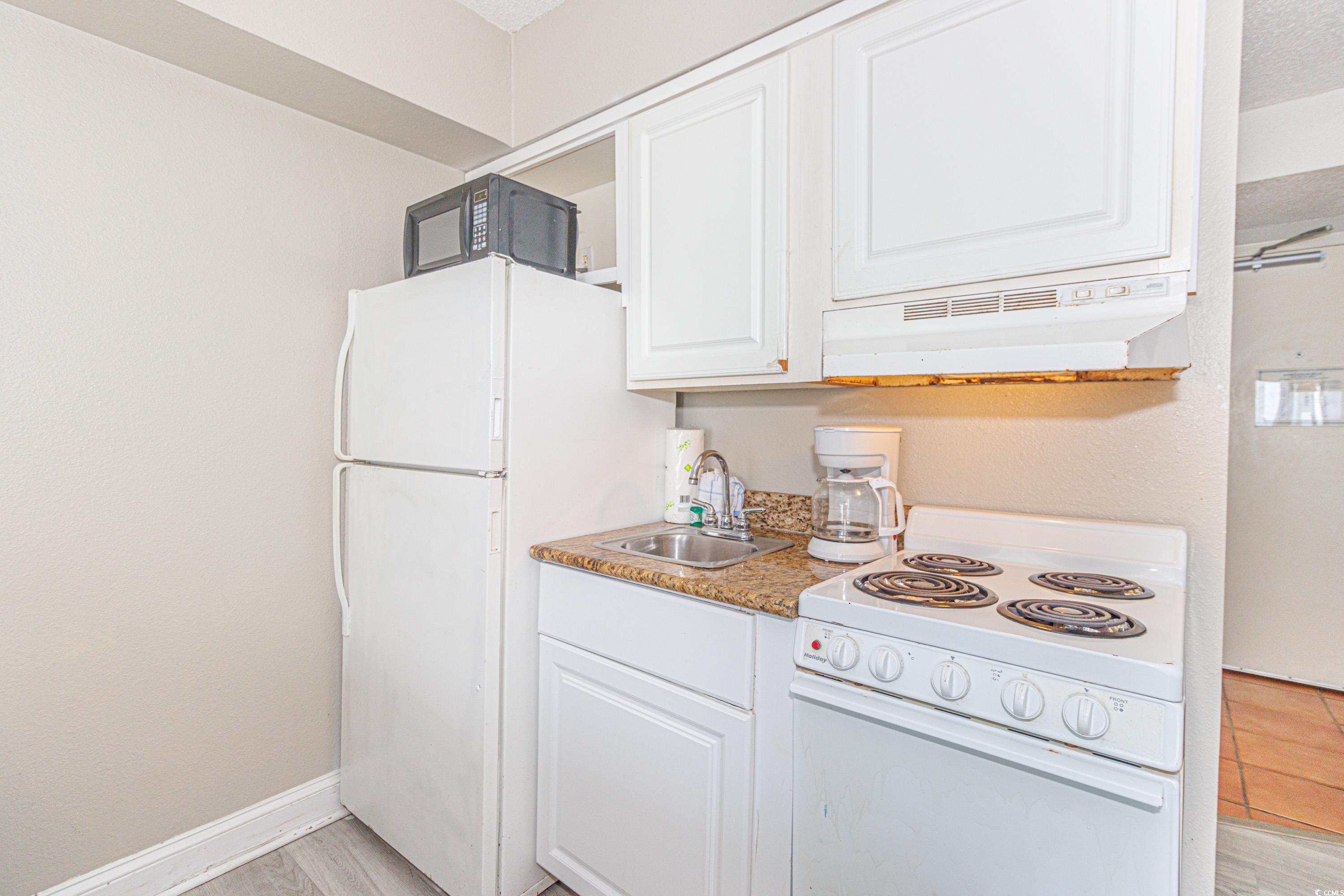 1207 South Ocean Boulevard, Unit 20703 Myrtle Beach, SC 29577 - Photo 12 of 22 Kitchen featuring light hardwood / wood-style floors, sink, a textured ceiling, white appliances, and white cabinets