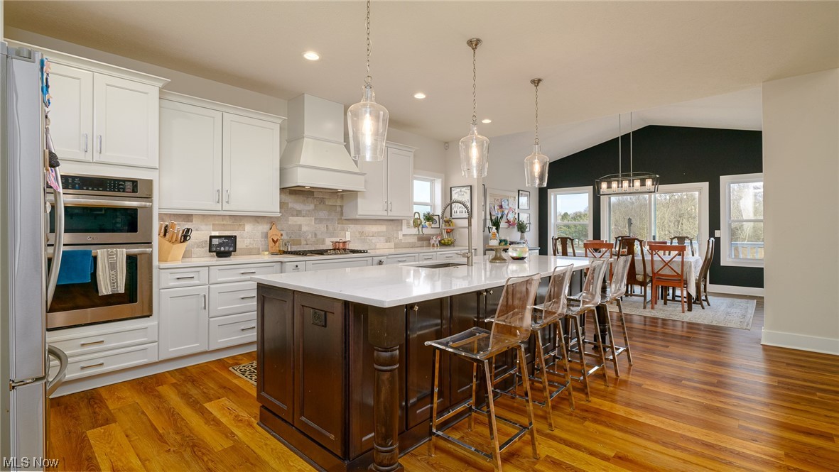 1849 Fixler Road Wadsworth, OH 44281 - Photo 21 of 39 Kitchen featuring dark hardwood / wood-style flooring, custom range hood, vaulted ceiling, hanging light fixtures, and stainless steel appliances