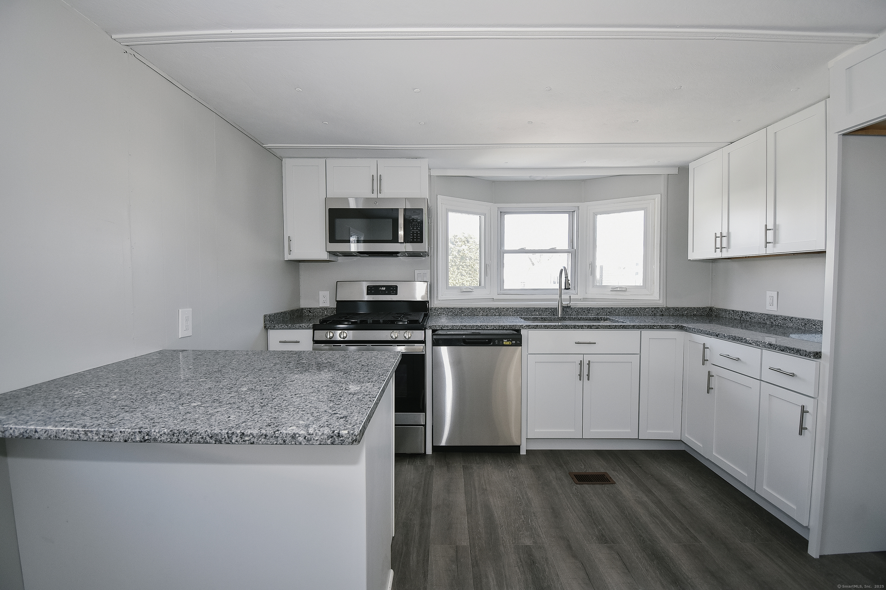 a kitchen with granite countertop a sink stainless steel appliances and white cabinets