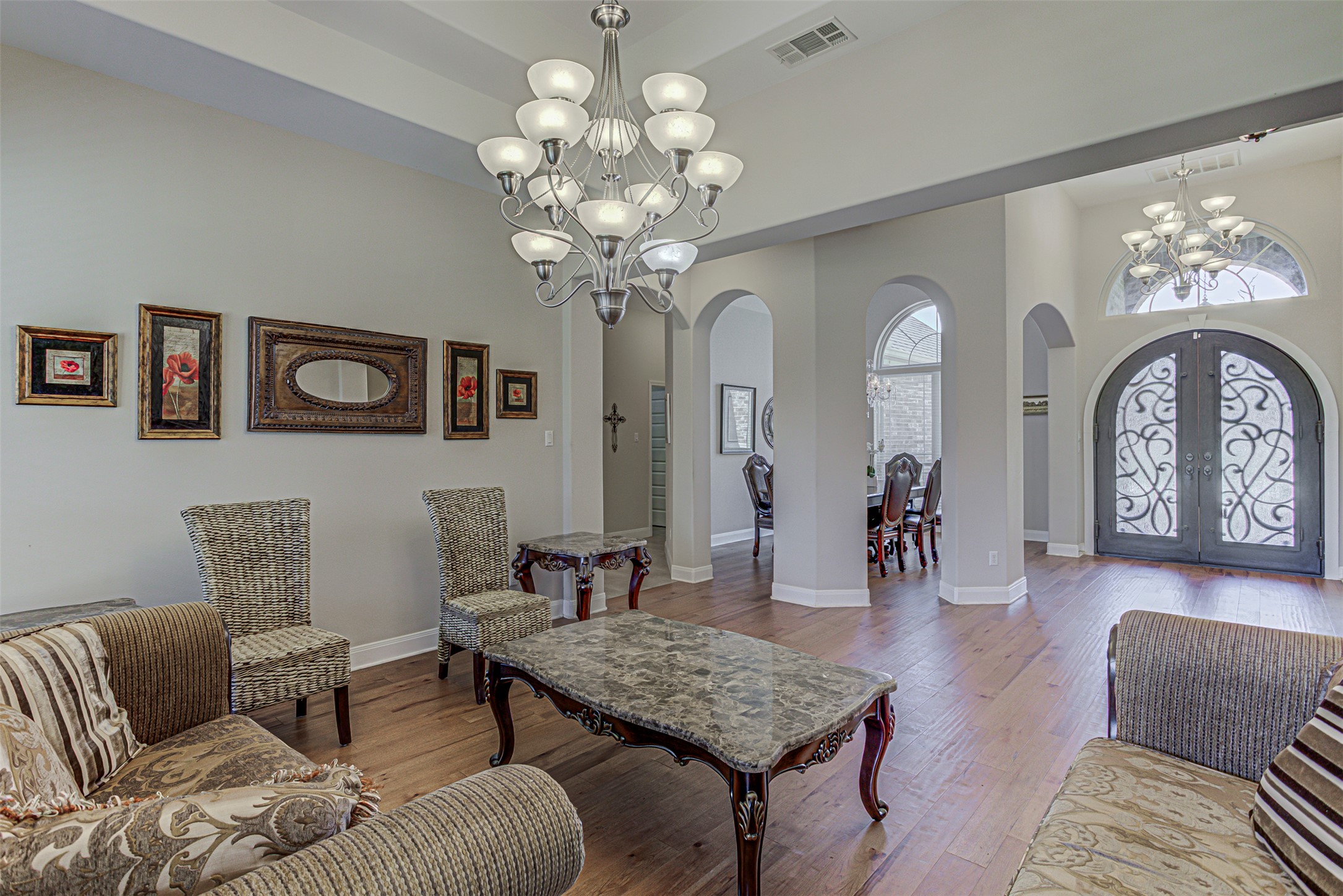 105 Arbors Circle Elgin, TX 78621 - Photo 11 of 40 Living room featuring a chandelier, arched walkways, wood finished floors, a high ceiling, and french doors